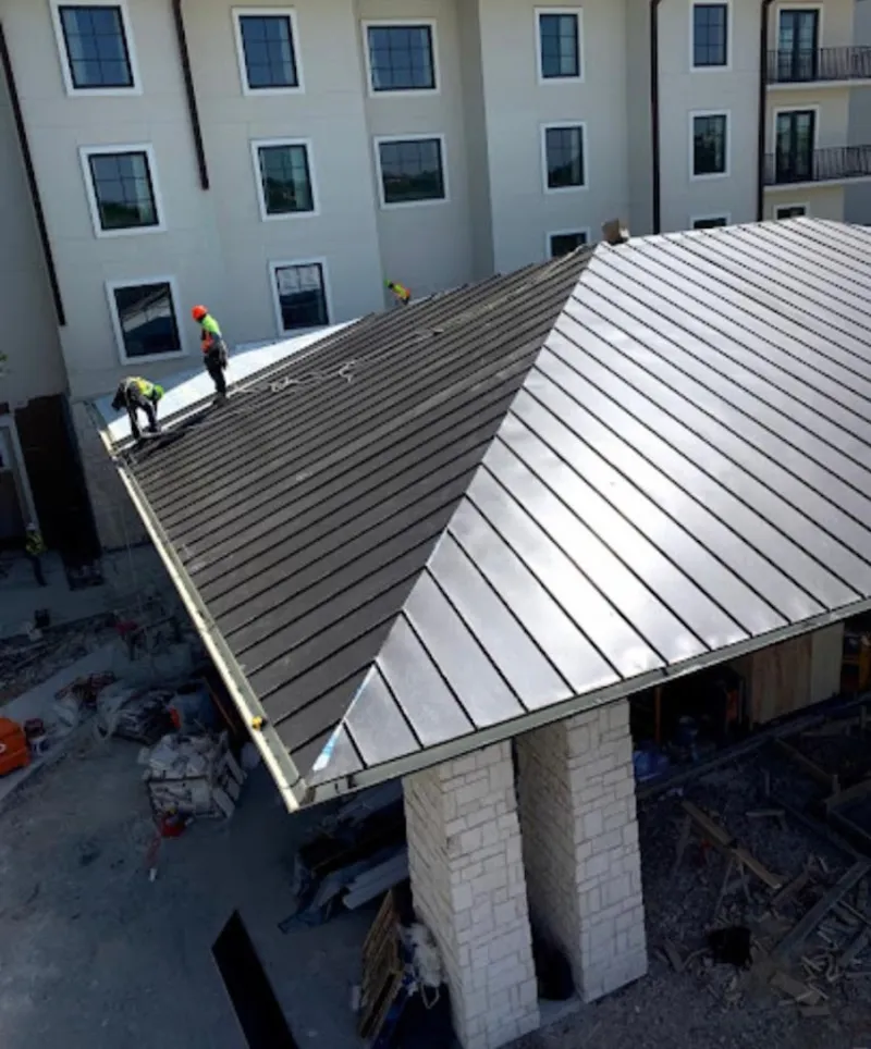 Crew installing standing seam metal roof panels on a commercial project in Belle Fourche